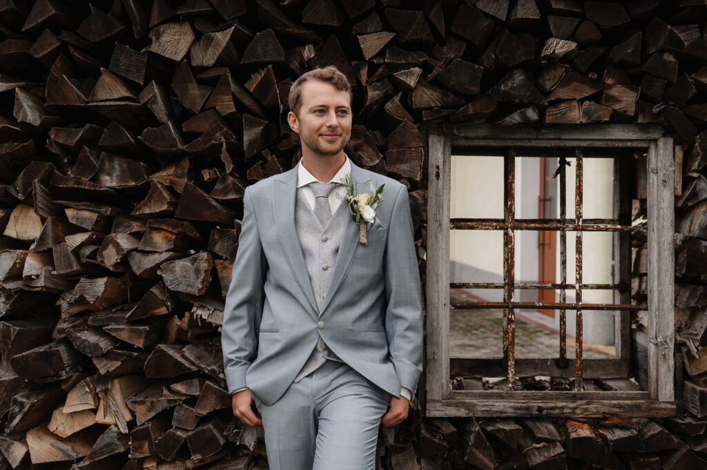 Bräutigam posiert vor einem Holzstoß