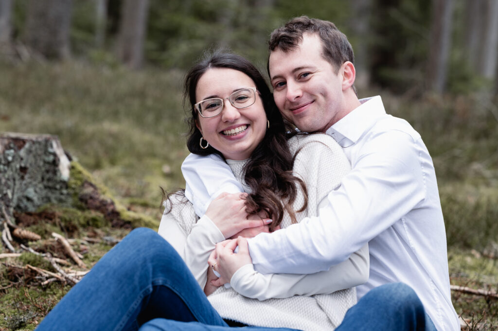 Liebendes Paar im Wald sitzend, Hände umschlungen