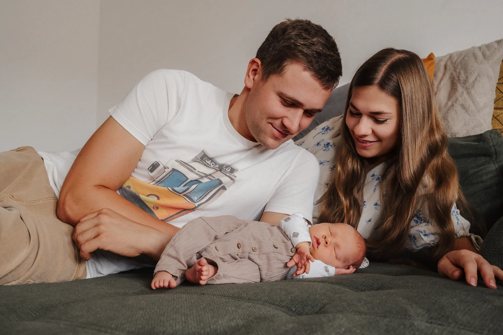Eltern betrachten ihr Baby liebevoll beim natürlichen Newbornshooting